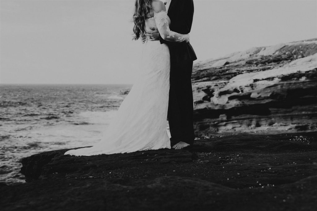 Bride and groom standing on the Hawaii coast during their adventure elopement.