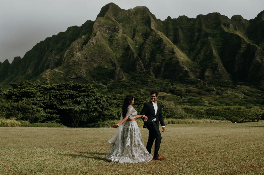 Bride and groom running through a field in Hawaii for their adventure elopement