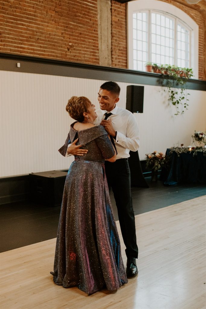 Groom smiling at his mom during mother-son dance.